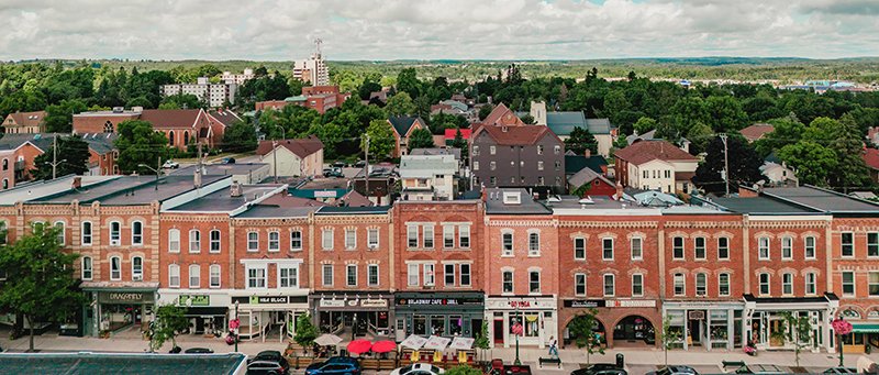 Downtown Orangeville A line of heritage buildings with trees and apartment buildings in the background