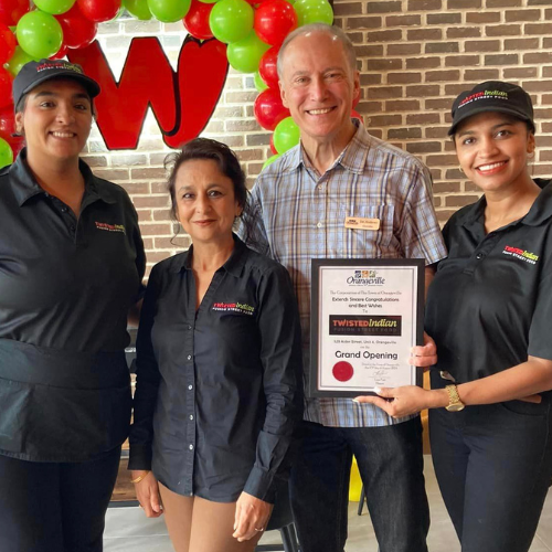 Three East Indian Women and one older white male smiling with a certificate