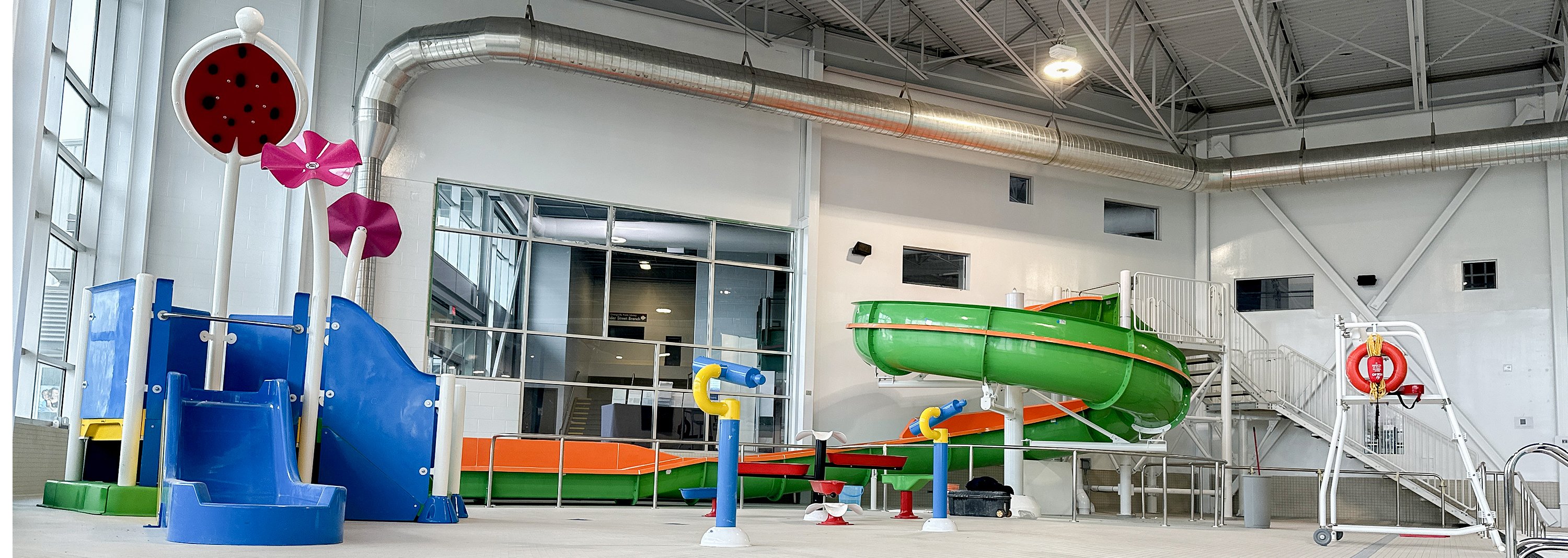 An indoor play area near a pool with two water slides and additional water features