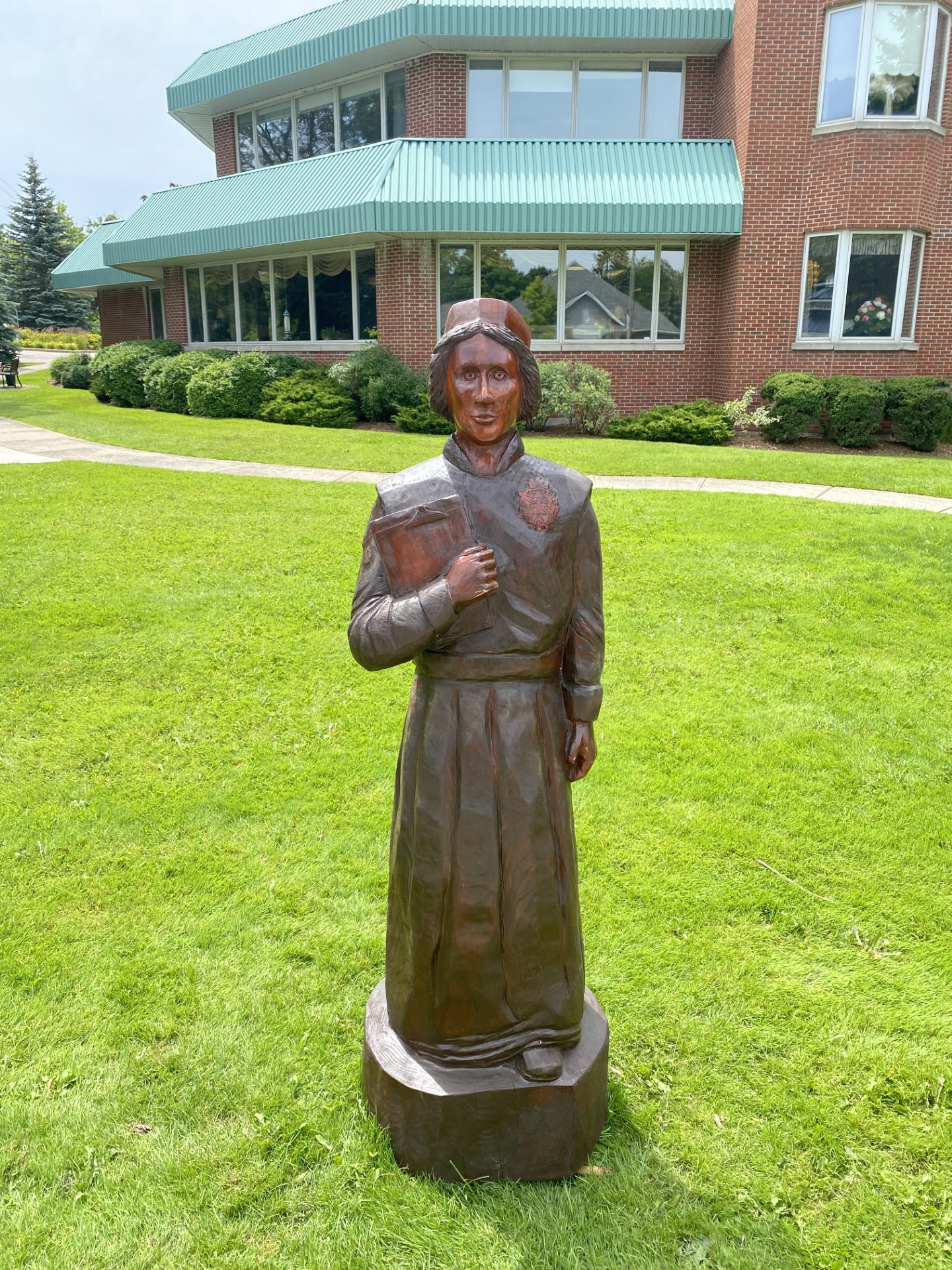 A wood statue of a nurse in front of a building