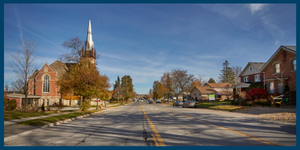 A picture of a road, with a large historic church on one side, and houses on the other.